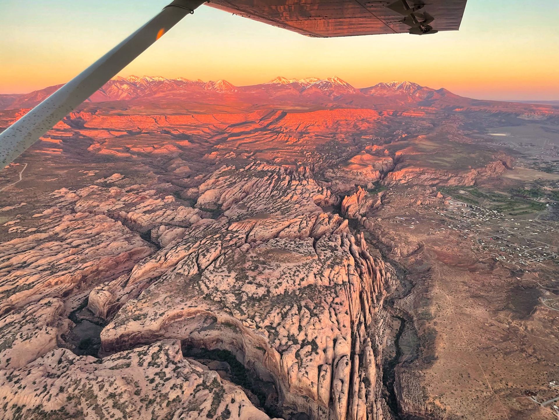 View from the window of an airplane overlooking dramatic canyons at sunset.