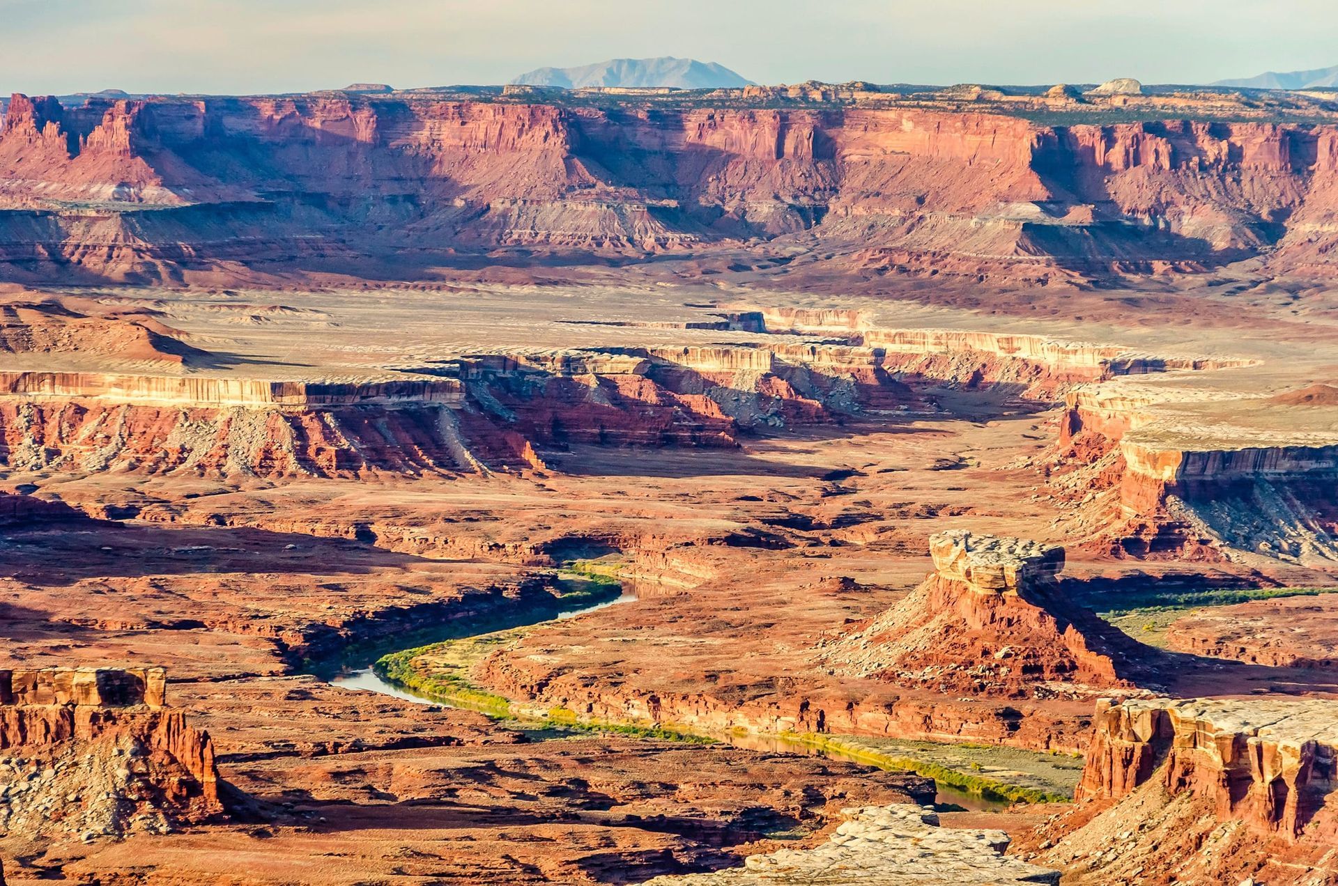 View from an airplane of a red rock canyon landscape with a meandering green river winding through the middle of the canyons.