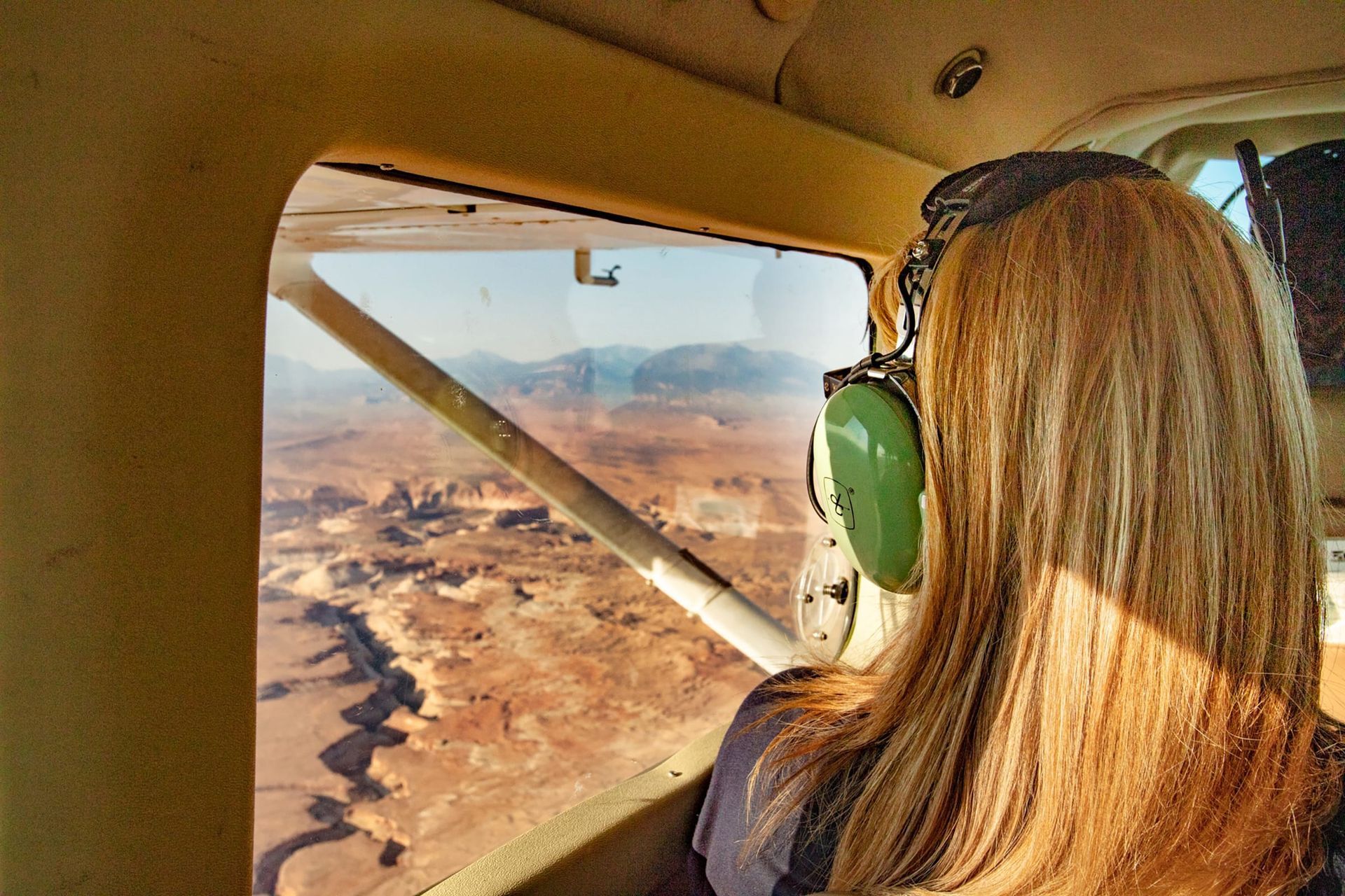A woman looks out the window of an airplane on a scenic flight over Canyonlands National Park.