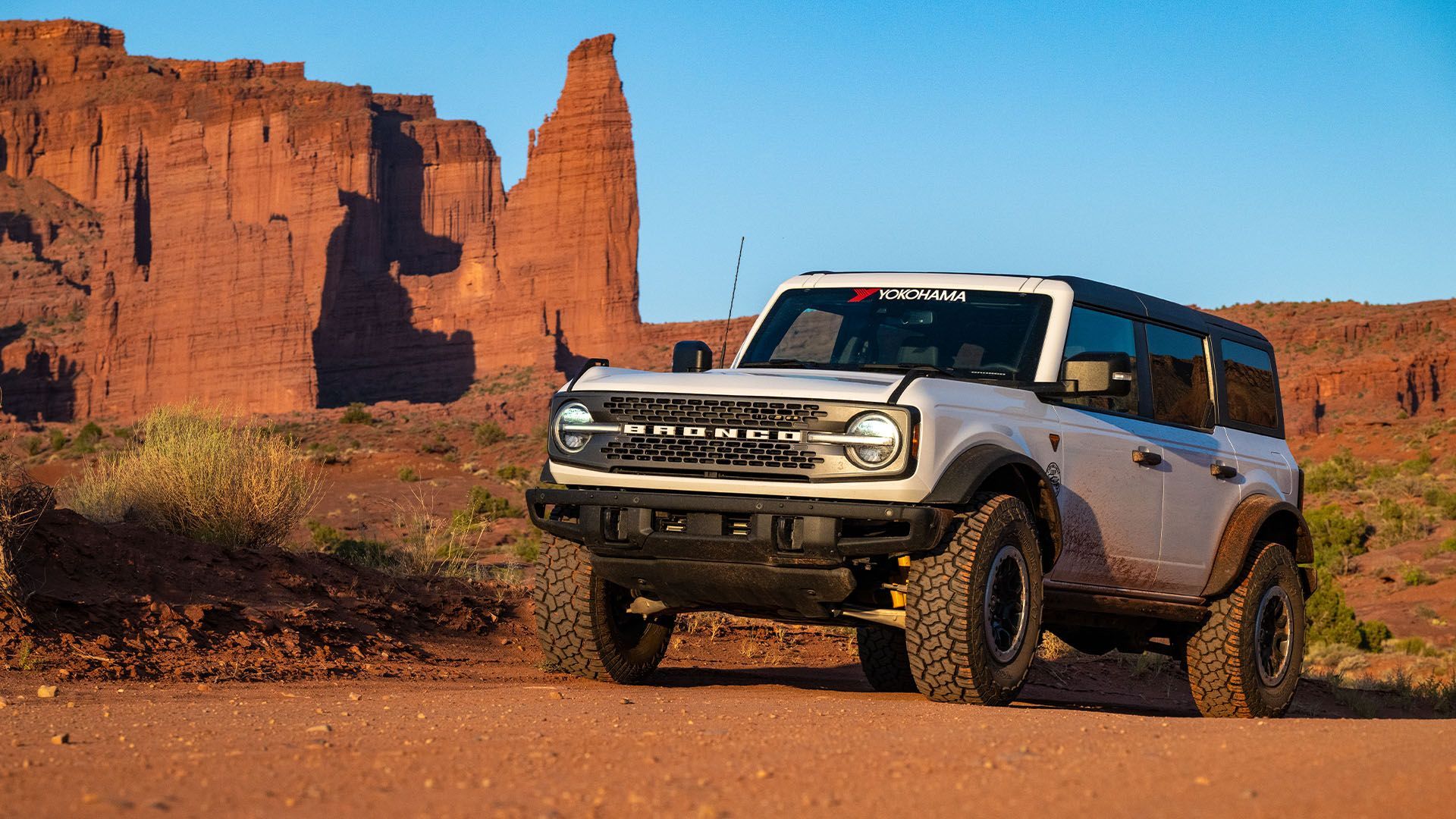 A white bronco is shown driving through the wilderness.