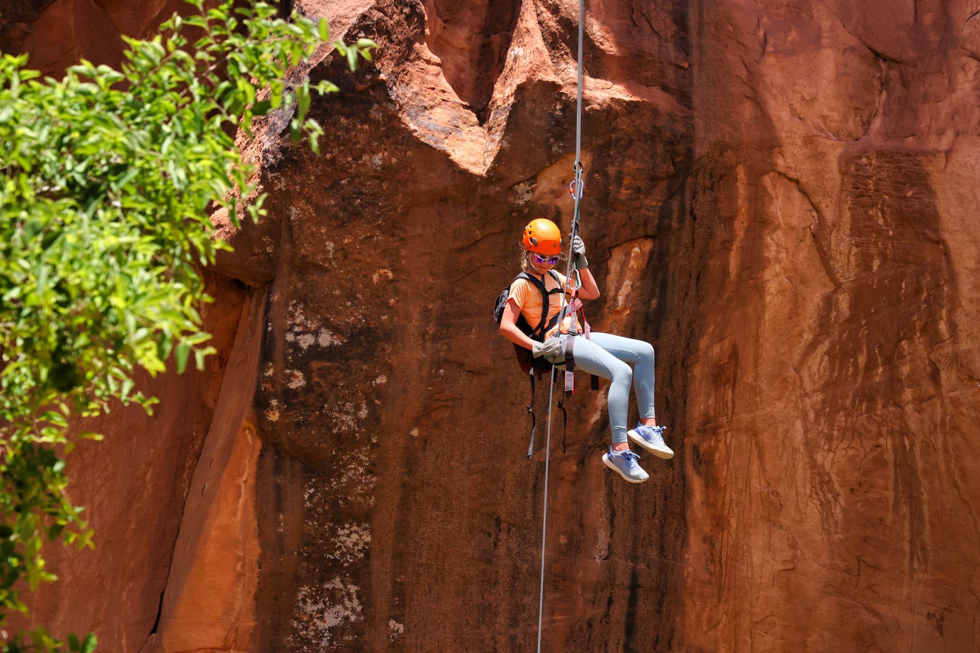 A person is hanging from a rope while climbing a rock wall.