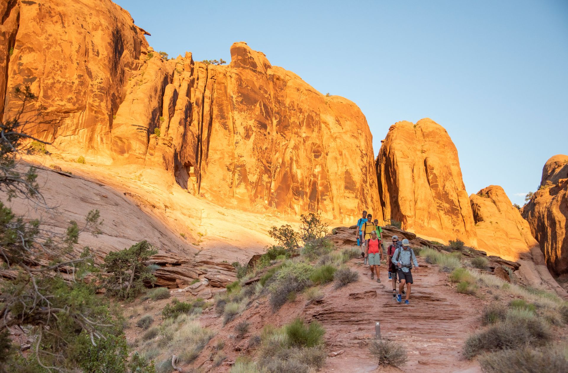 Hikers descend through Grandstaff Canyon with tall cliffs behind.