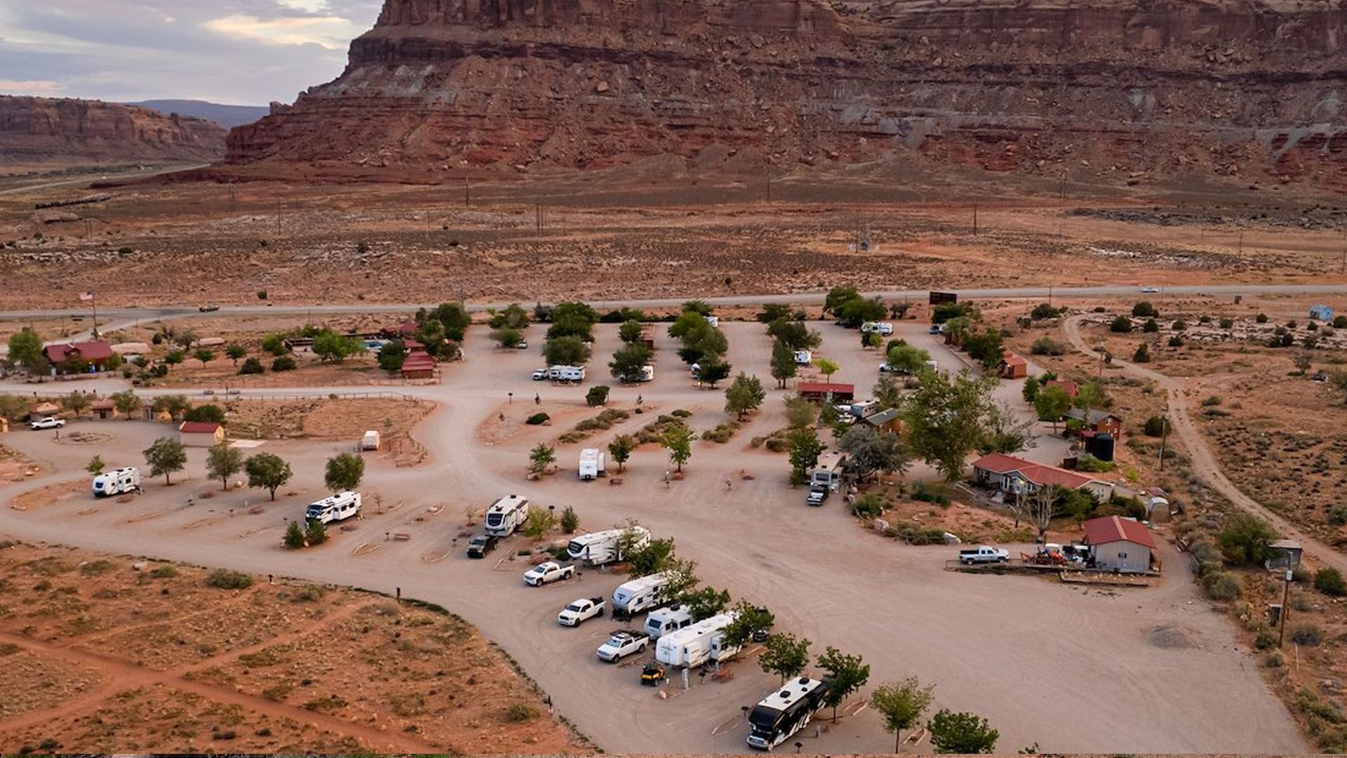 RV park in desert landscape with red rock cliffs in background.
