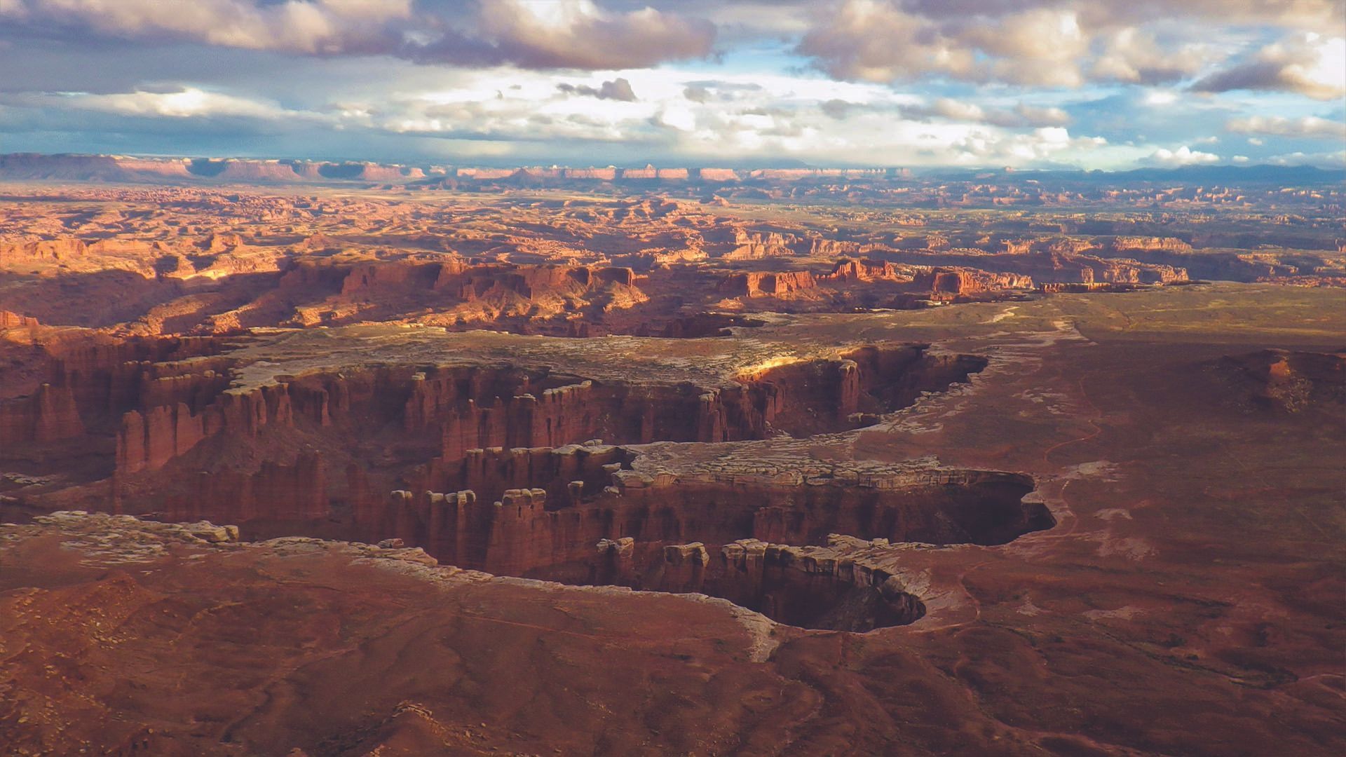 Canyonlands National Park, Utah: expansive desert landscape with red rock formations under a cloudy sky.