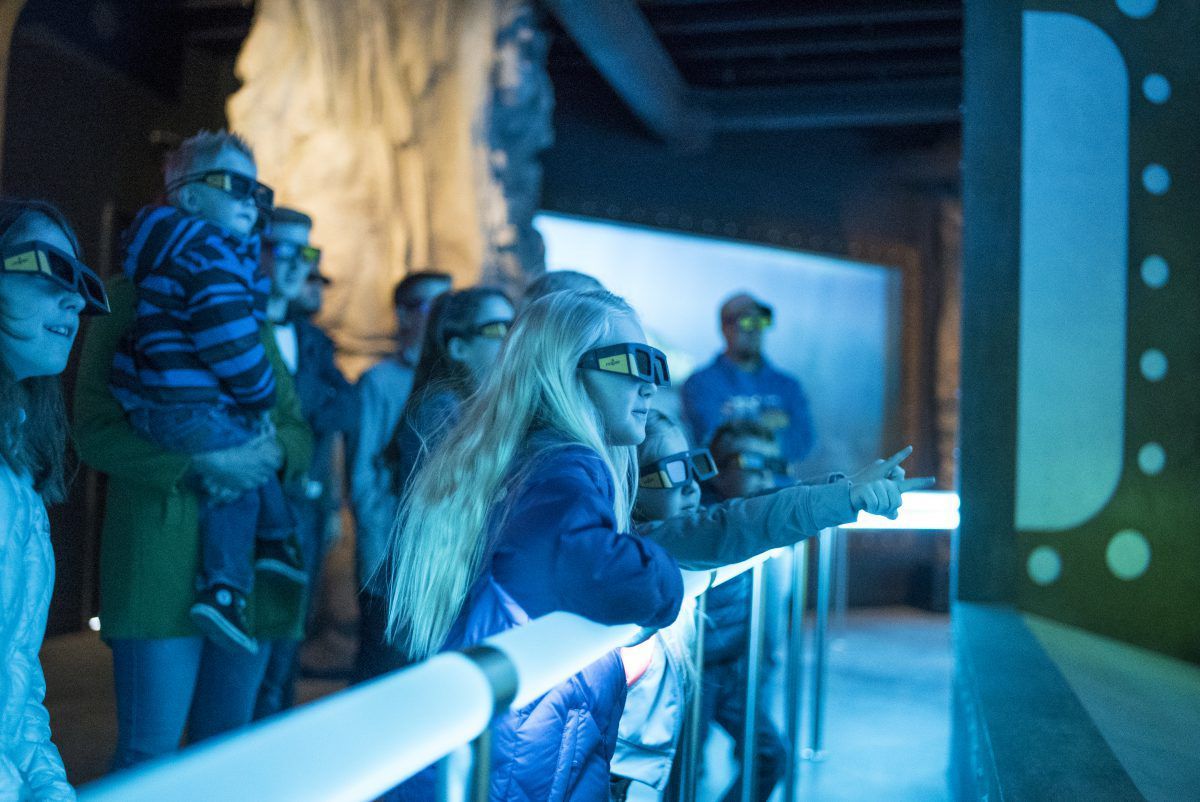 Children look at a 3D screen inside a museum in Moab as they learn about dinosaurs.
