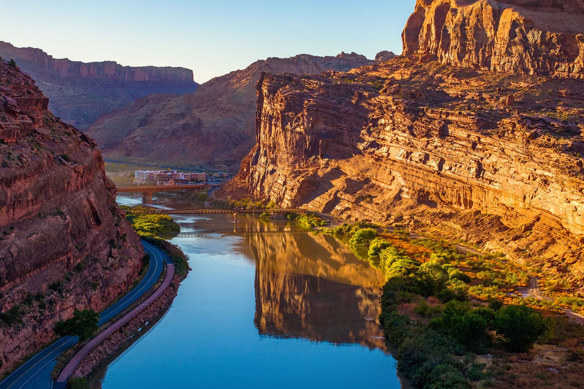 River winds through red rock canyon with a road along its edge. A hotel property sits in the distance overlooking the scene.