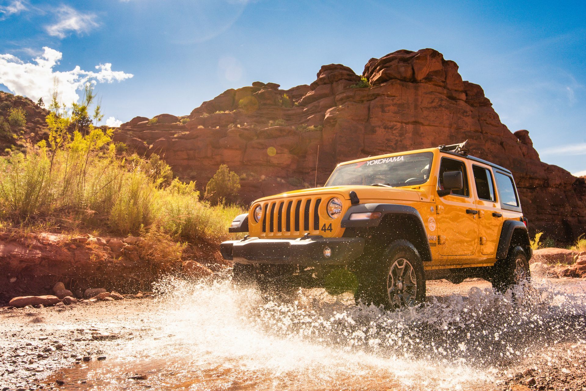 A yellow Jeep splashes through Onion Creek, exploring the off-road trails near Moab.
