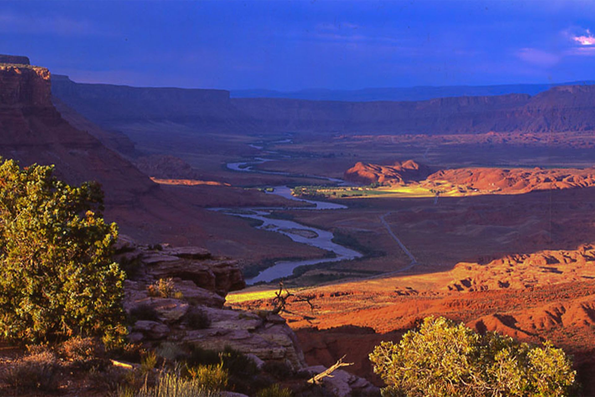 The Colorado River winds through Castle Valley, showing a wide expanse of desert.