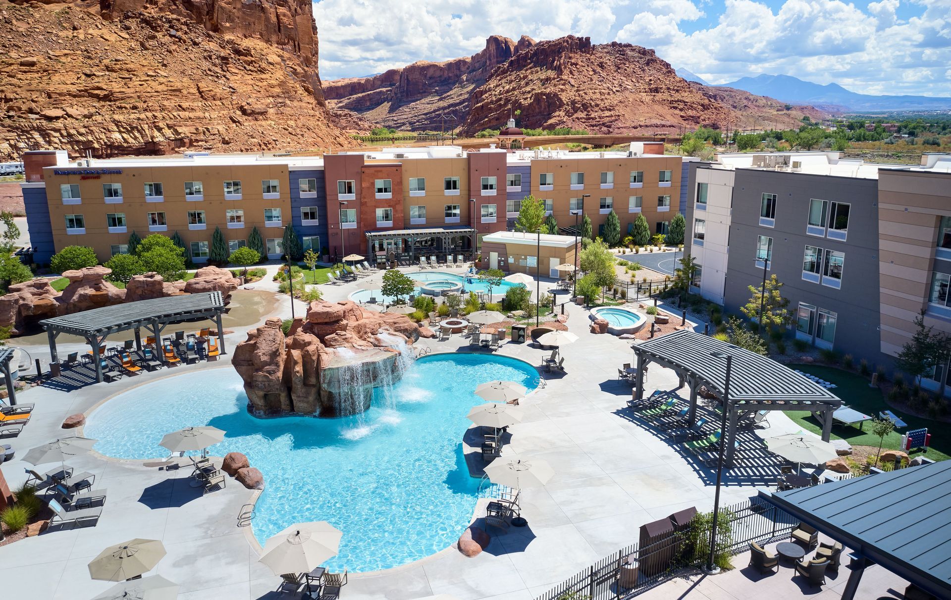 Hotel with pool and red rock backdrop.