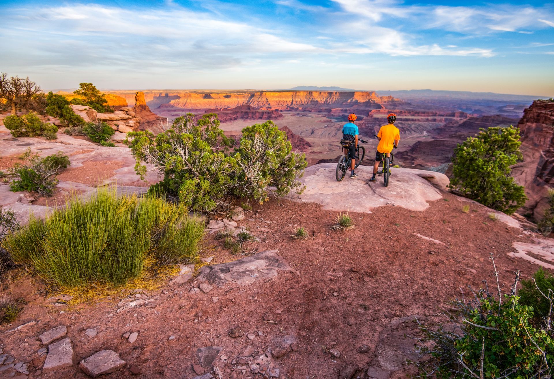 A couple of people standing on top of a mountain looking at the grand canyon.
