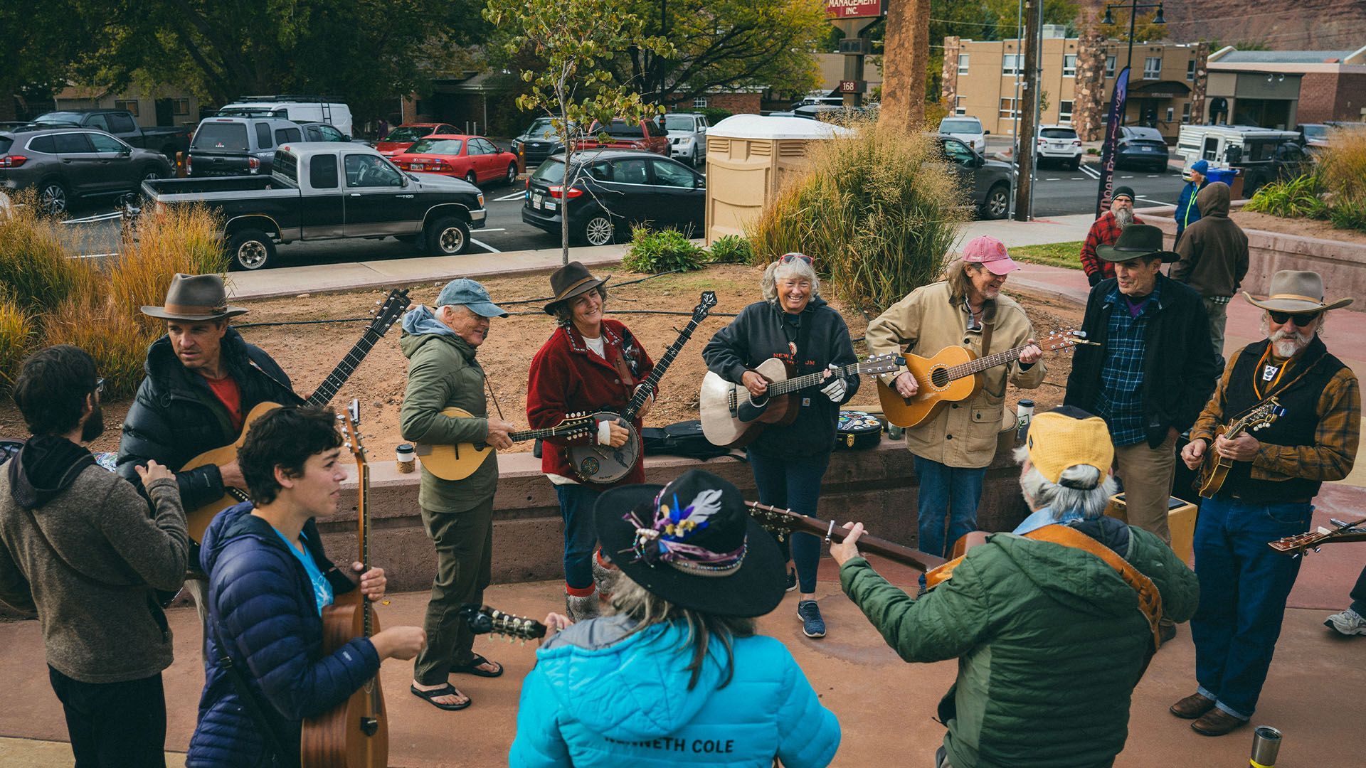 A group of people playing stringed instruments outdoors in a park.