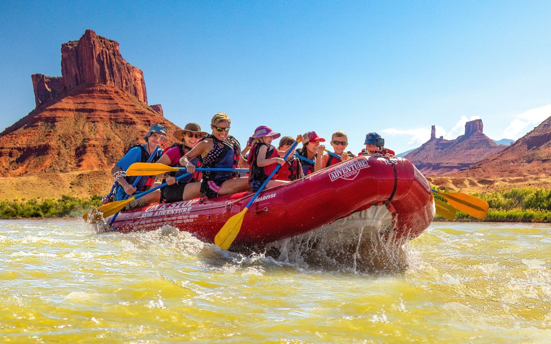 Rafting on a river with a group of people, red raft, scenic desert landscape.