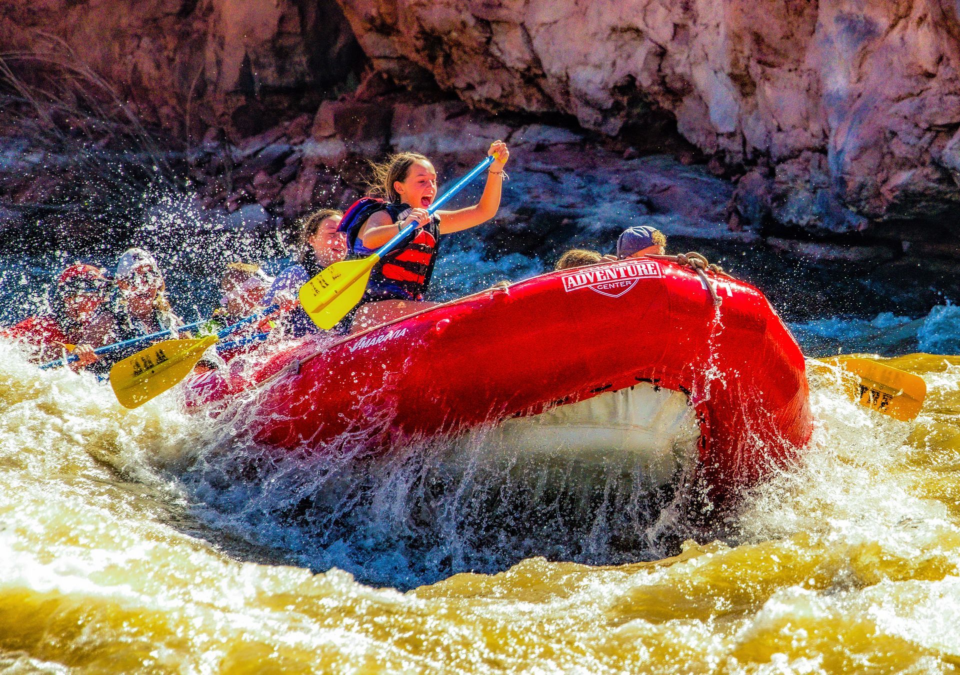A group of people are rafting down a river in a red raft.