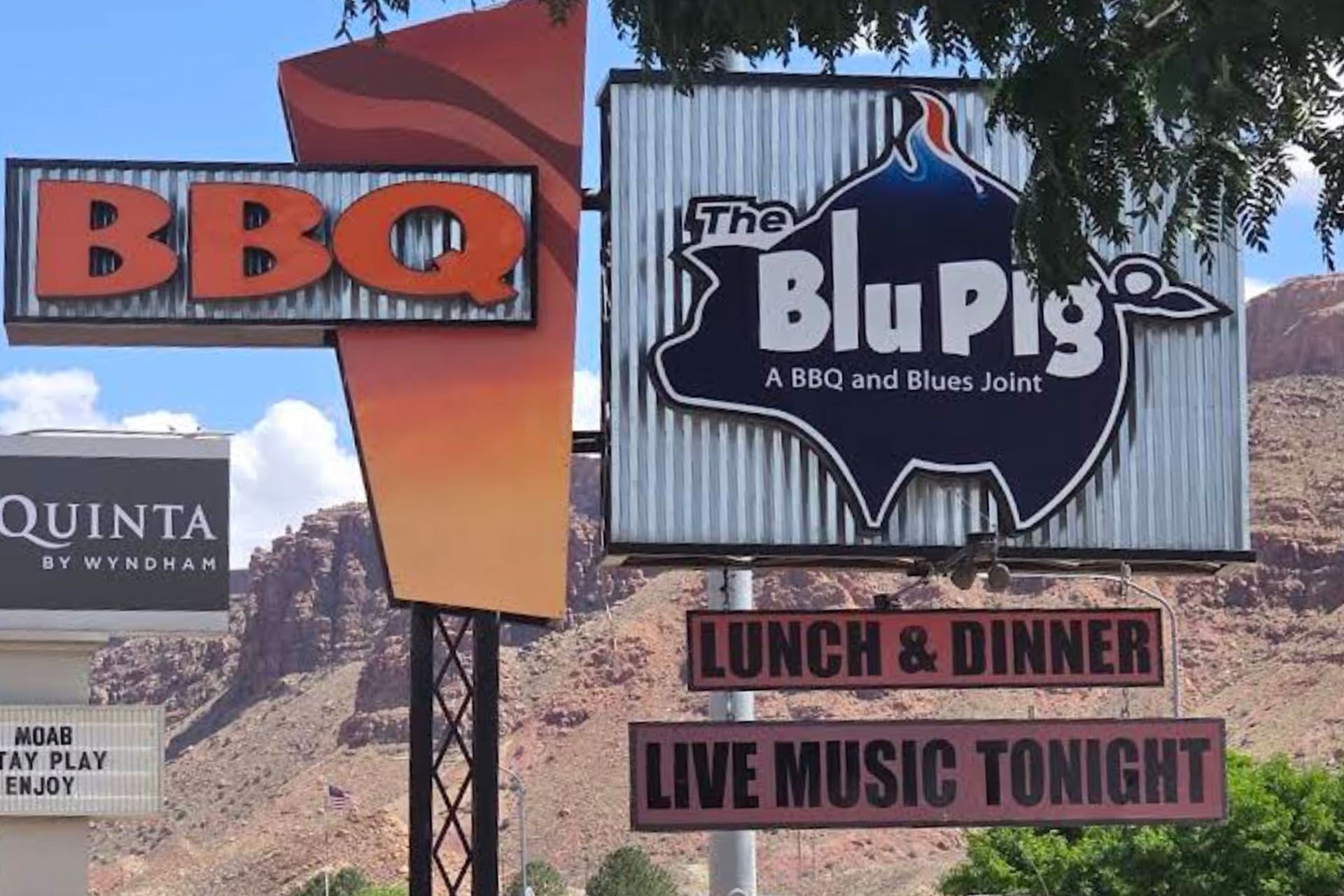 Large metal sign with the Blu Pig logo with BBQ, lunch and dinner, and live music tonight.