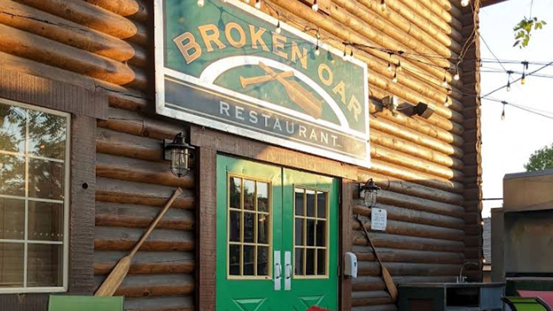 Broken Oak Restaurant sign above green double doors in a log cabin building.