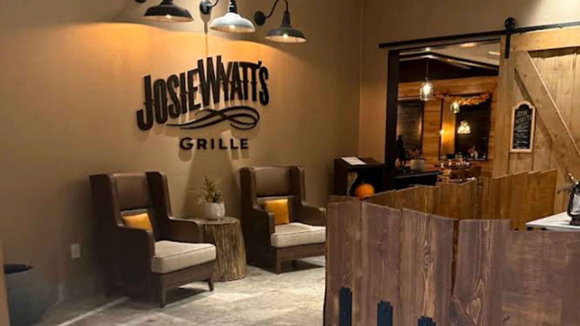 Josie Wyatt's Grille entrance: two armchairs, sign, rustic wood trim, open door to dining area.