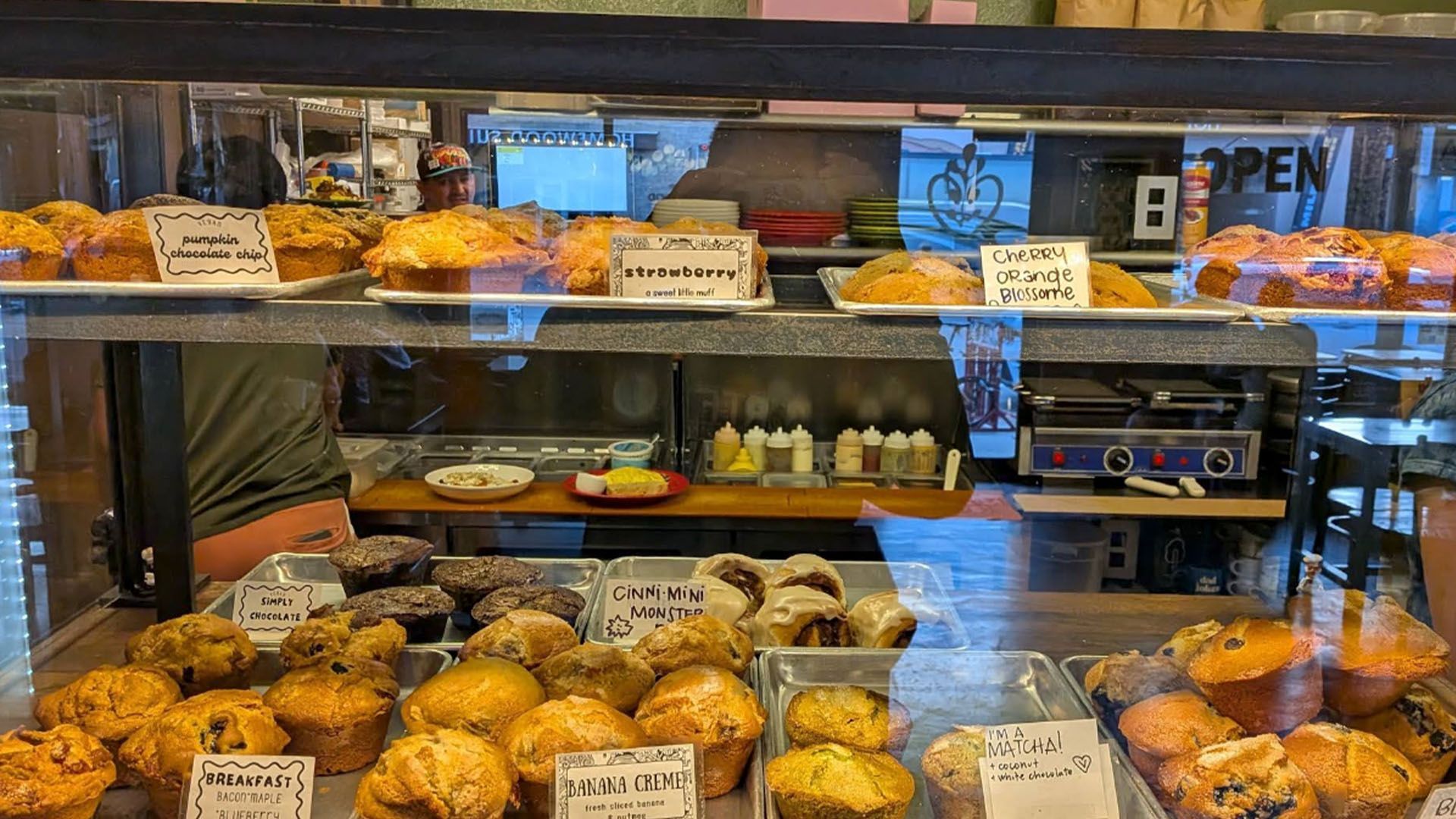 Display case filled with baked goods in a cafe, including muffins and pastries.