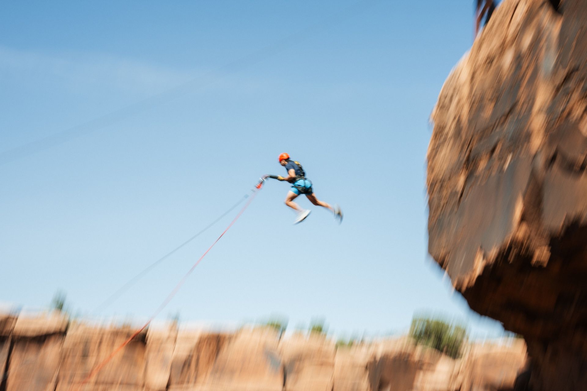 A guest jumping from the cliff on the Moab Rope Swing seen from a side view slightly below the jumper