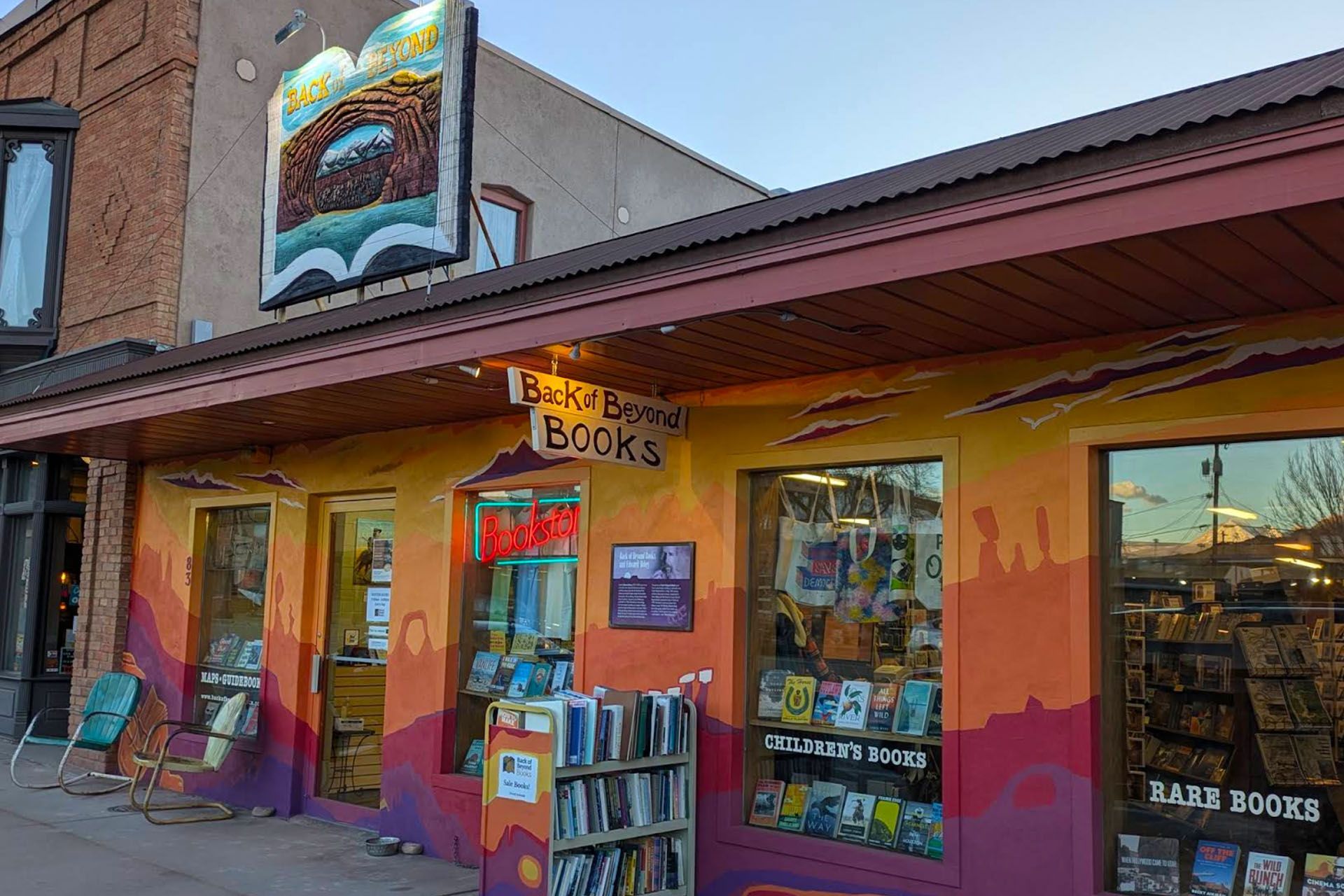 Colorful bookstore facade with mural, books in windows, and sign 