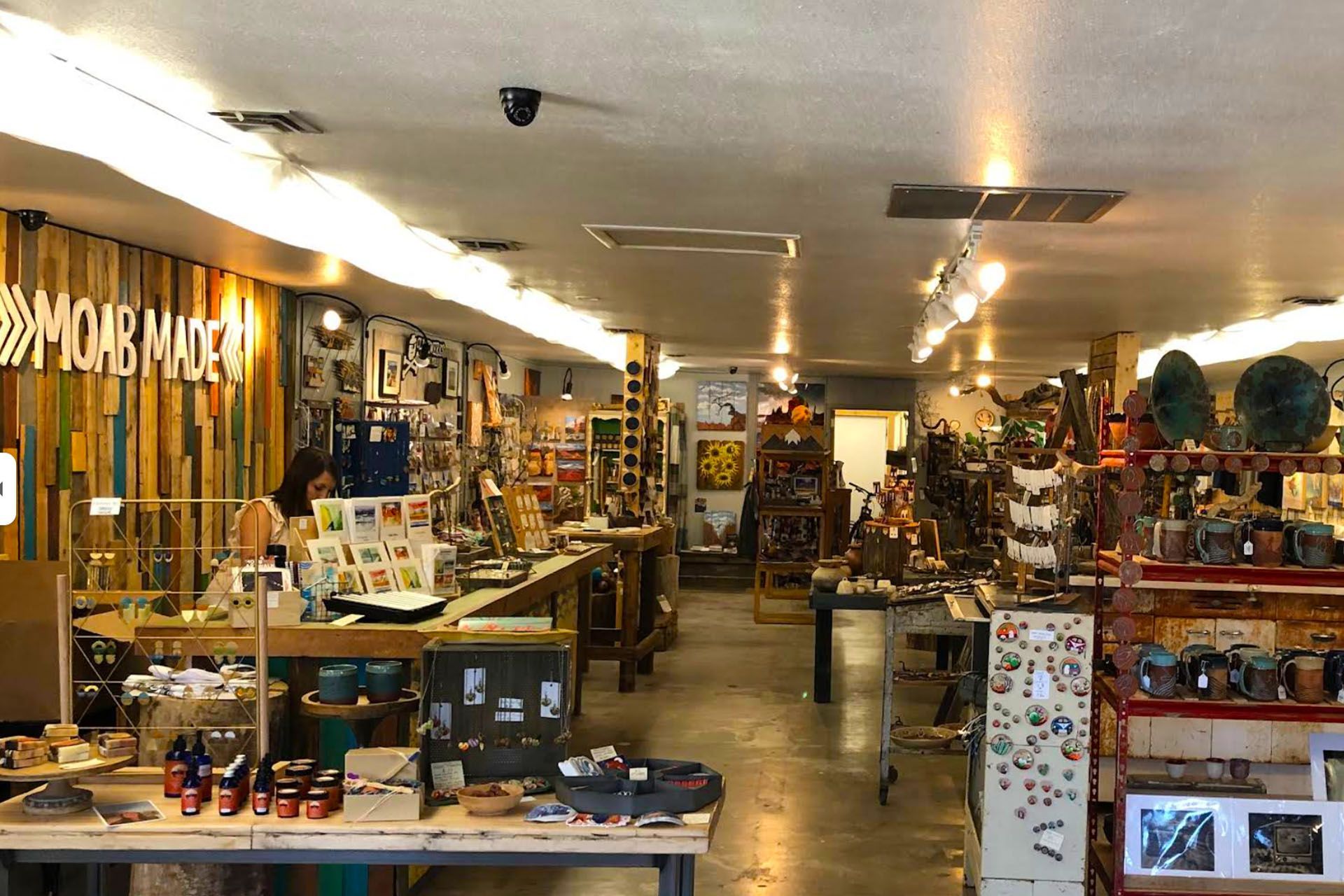Inside a shop: tables and shelves display art, crafts, and souvenirs.