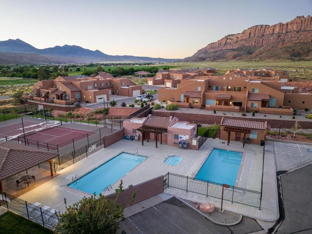 Pools and vacation rental buildings at resort with dramatic cliffs in the background.