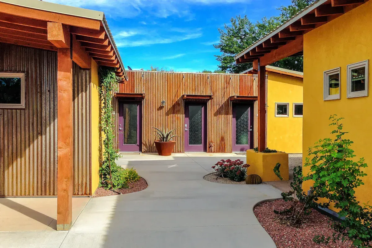 Courtyard with buildings of yellow and brown; purple doors, a blue sky.