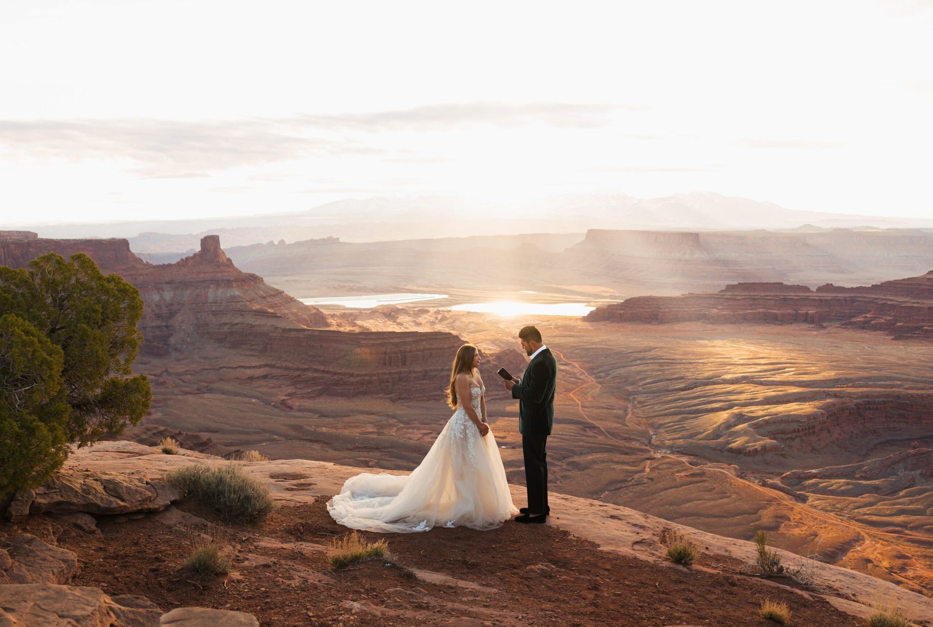 Bride and groom at a desert wedding ceremony. Sunset illuminates the vast landscape.