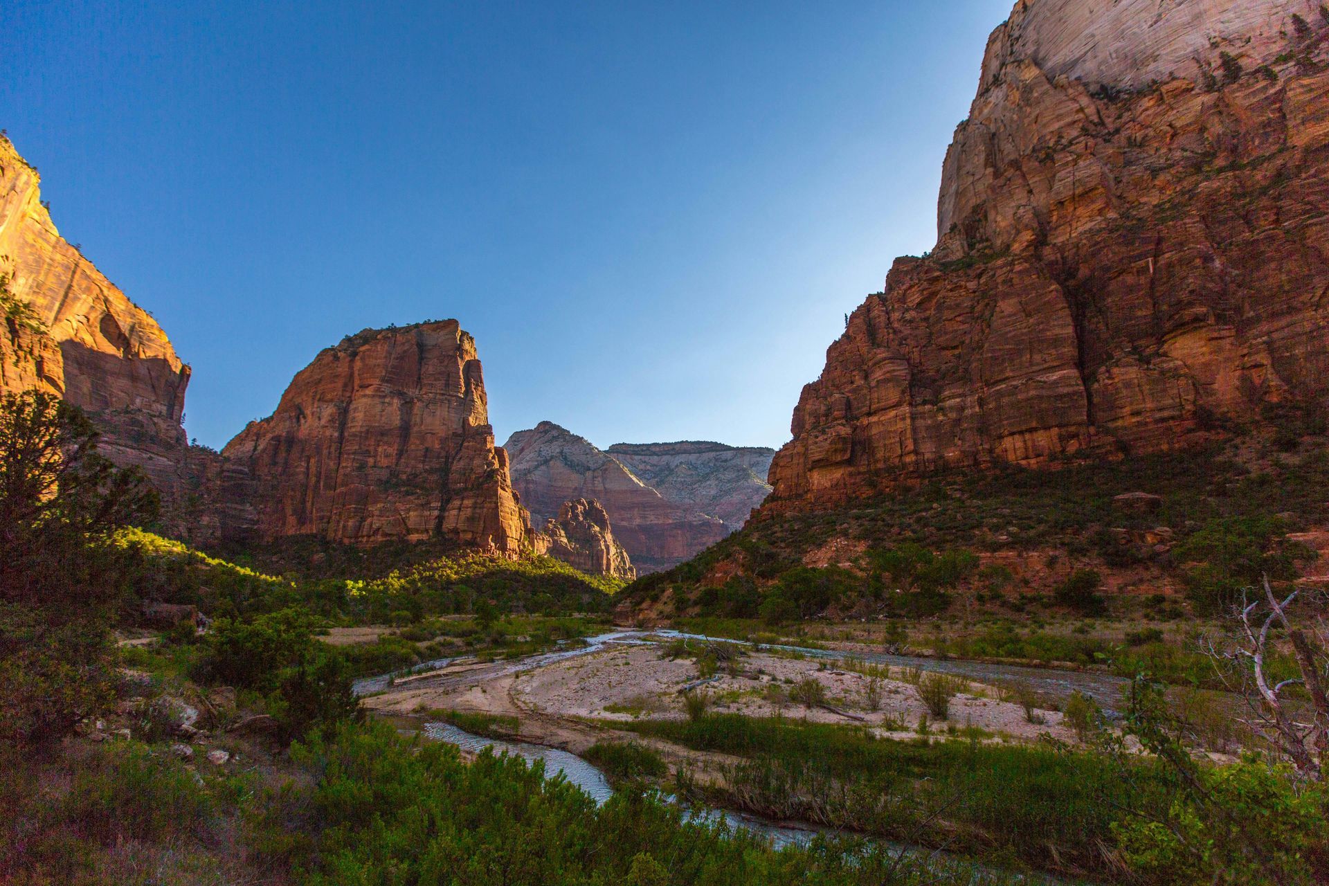 Canyon landscape with sandstone cliffs, a river, and blue sky.