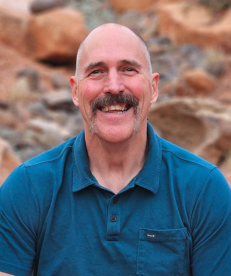 Trent Keller smiling with red rock scenery behind him.