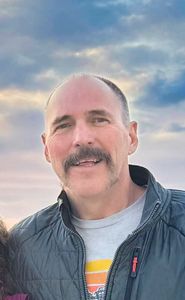 Trent Keller smiling with a sunset behind.