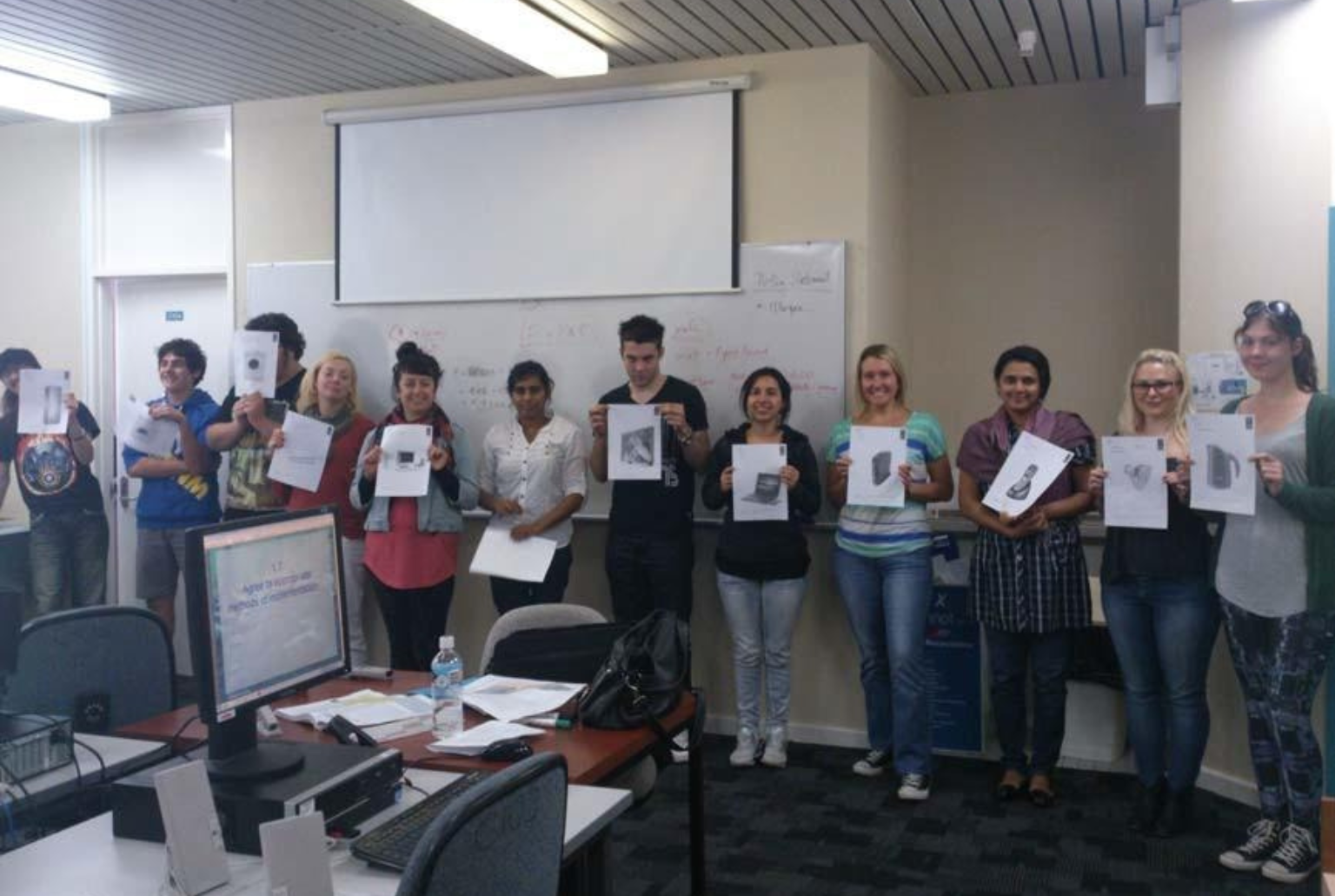 Group of people at Camelia's workshop holding up their work