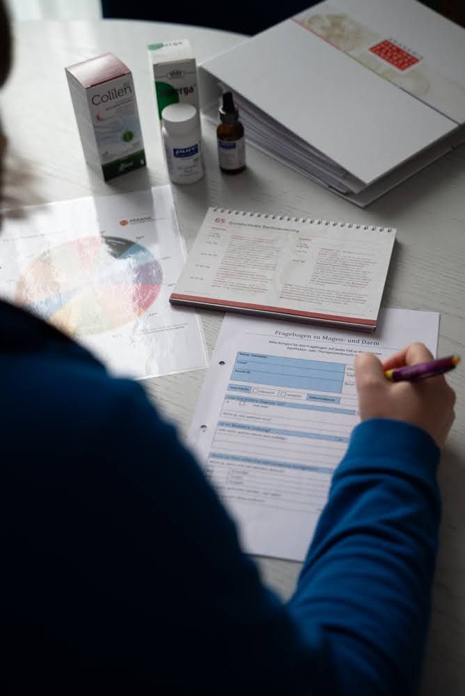Eine Person sitzt an einem Tisch und schreibt auf ein Blatt Papier