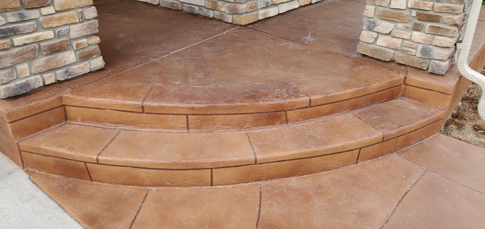 Curved concrete steps with brown and tan brickwork, leading to a doorway.