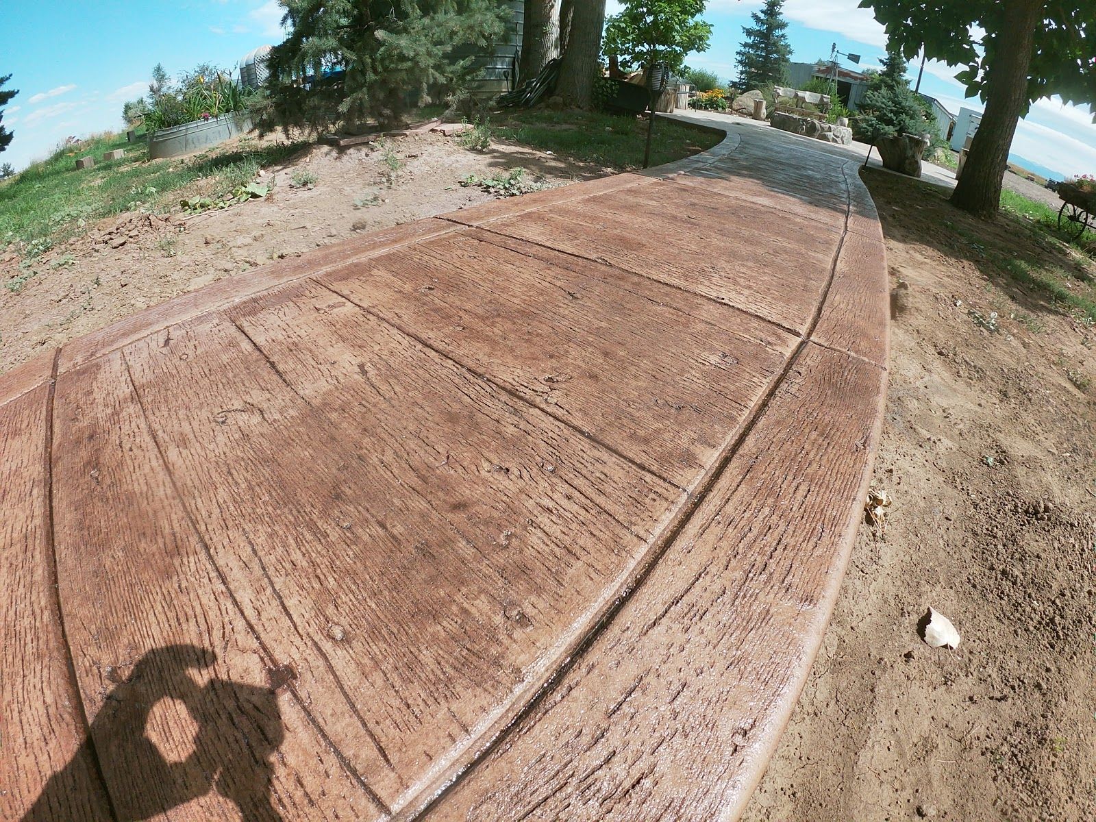 Brown stamped concrete walkway with wood grain pattern outdoors.
