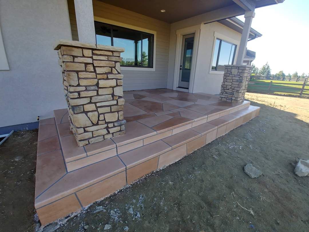 Stone patio with steps, two stone columns, and a tan building.