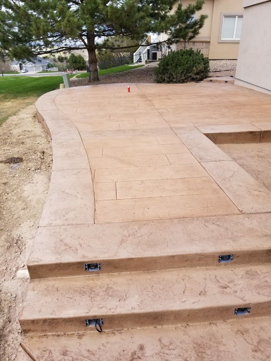 Brown stamped concrete patio with steps and embedded lights.