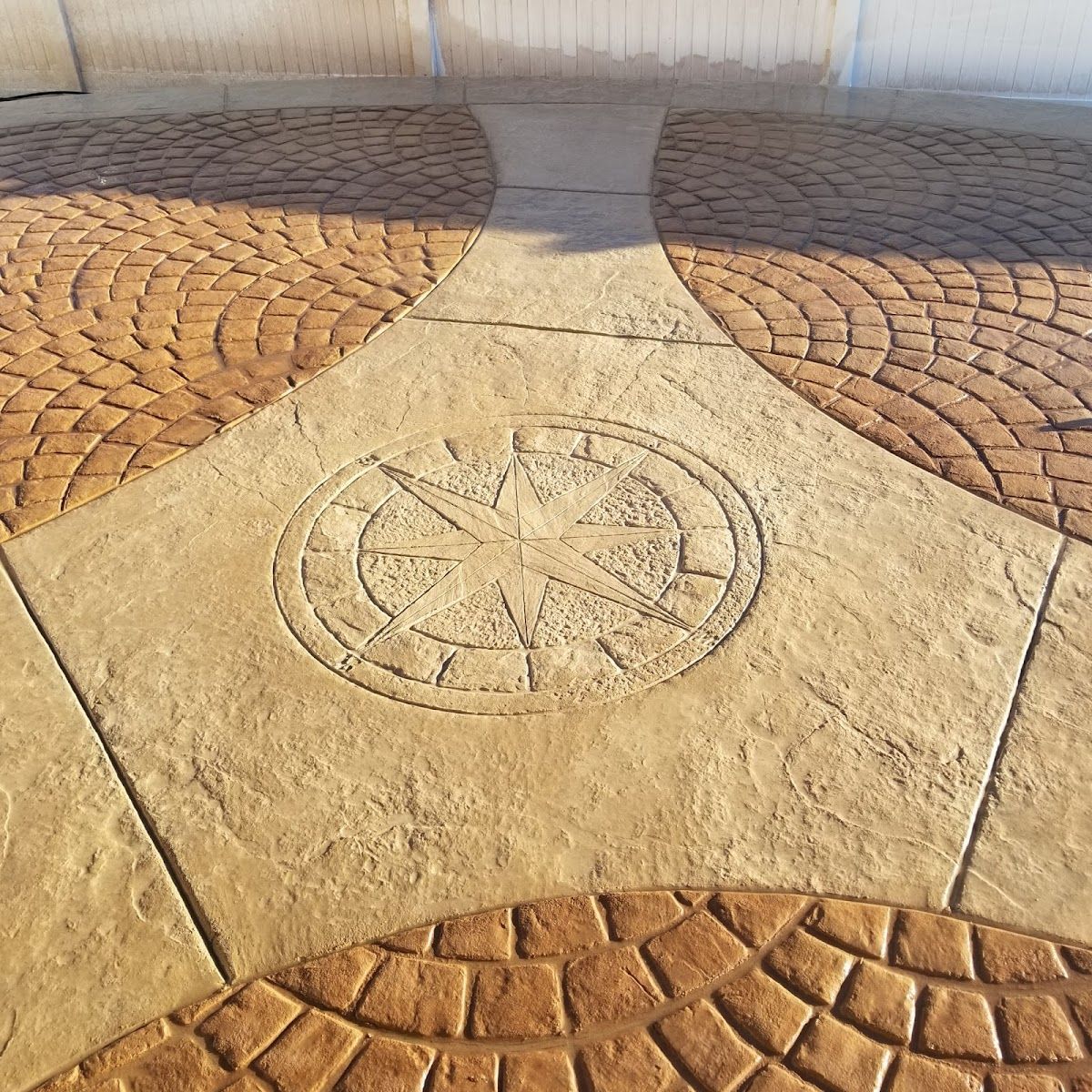 Stamped concrete patio with compass design and arched brickwork pattern.
