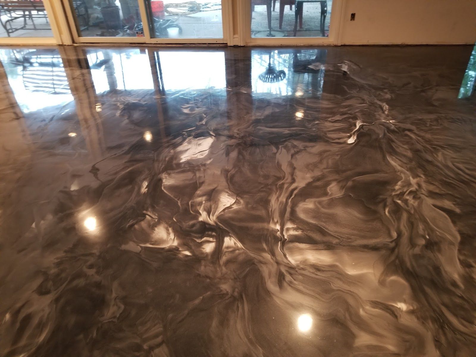 Metallic epoxy flooring in shades of gray and silver with swirling patterns, reflecting light.