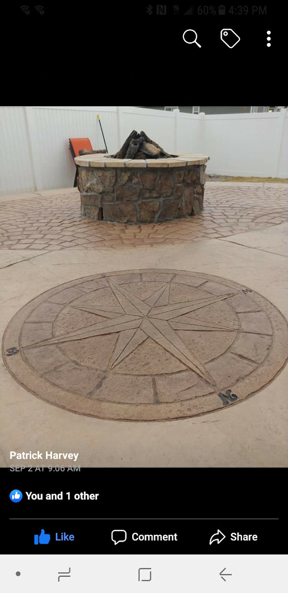 A stone compass design etched into concrete patio with a fire pit in the background.