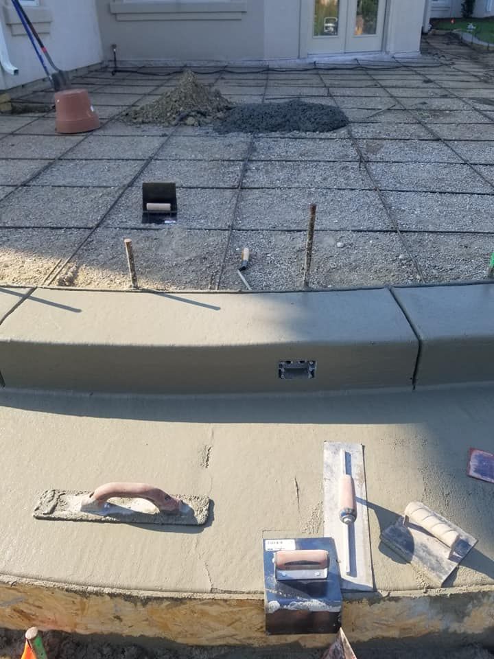 Concrete patio construction in progress with tools, rebar, and a fresh pour.