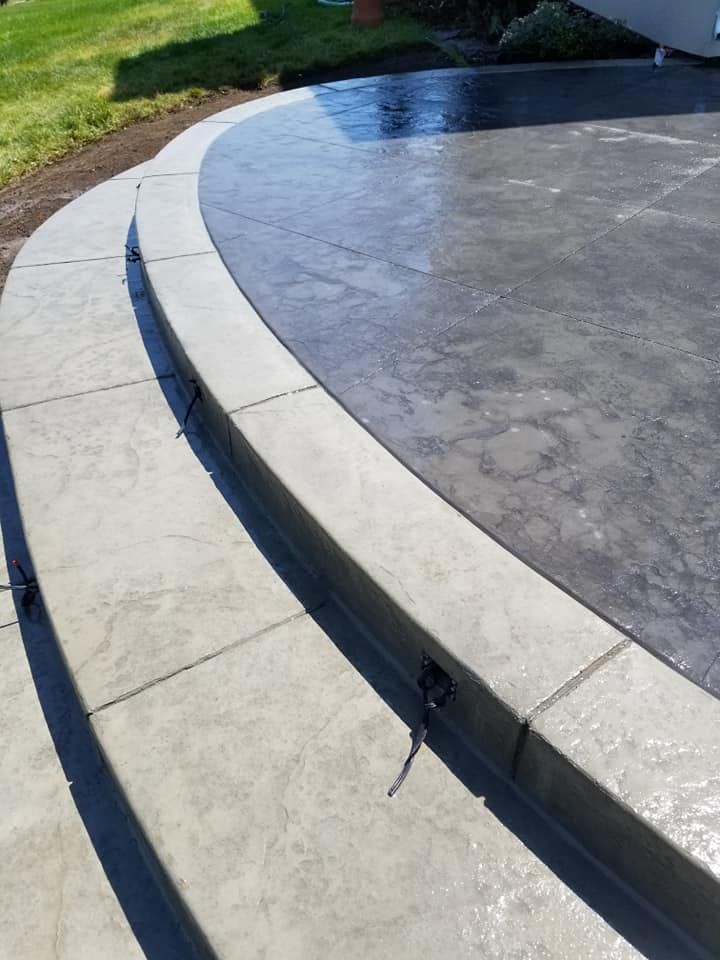 Concrete steps and patio with curved edges; gray and light gray.