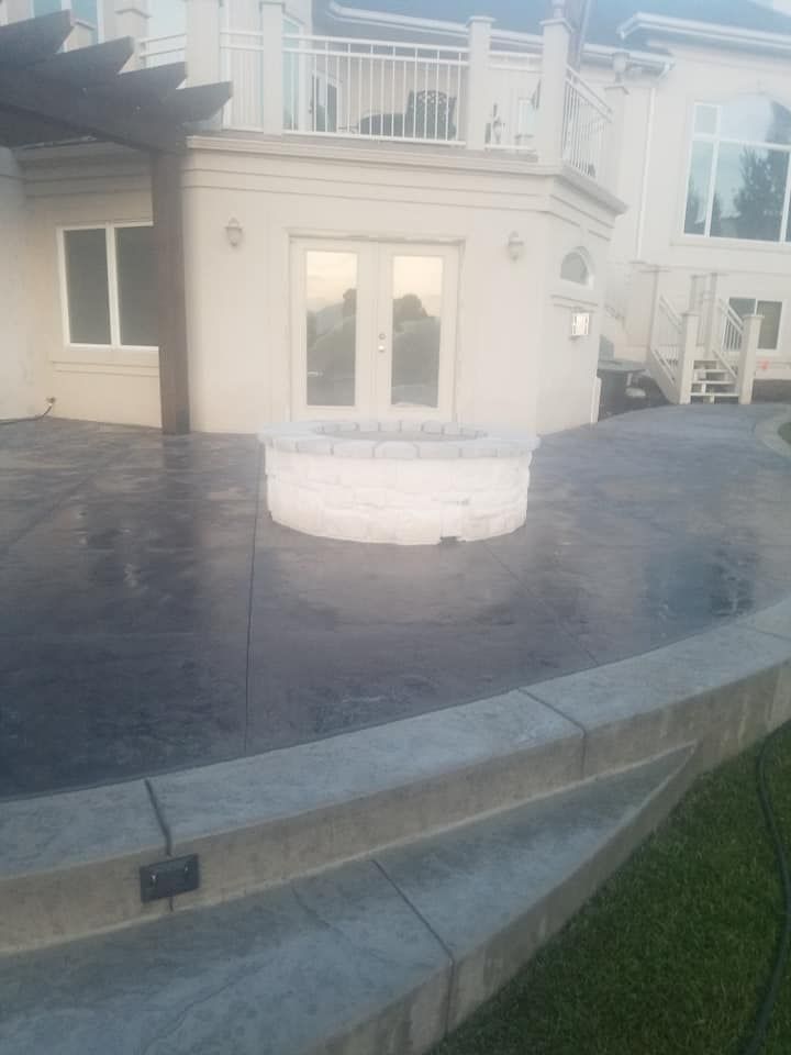 Concrete patio with fire pit, French doors, and a two-tiered concrete wall. Overcast, outdoor setting.
