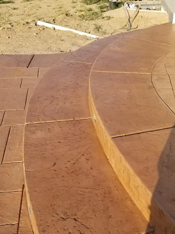 Brown stamped concrete steps and patio leading outdoors.