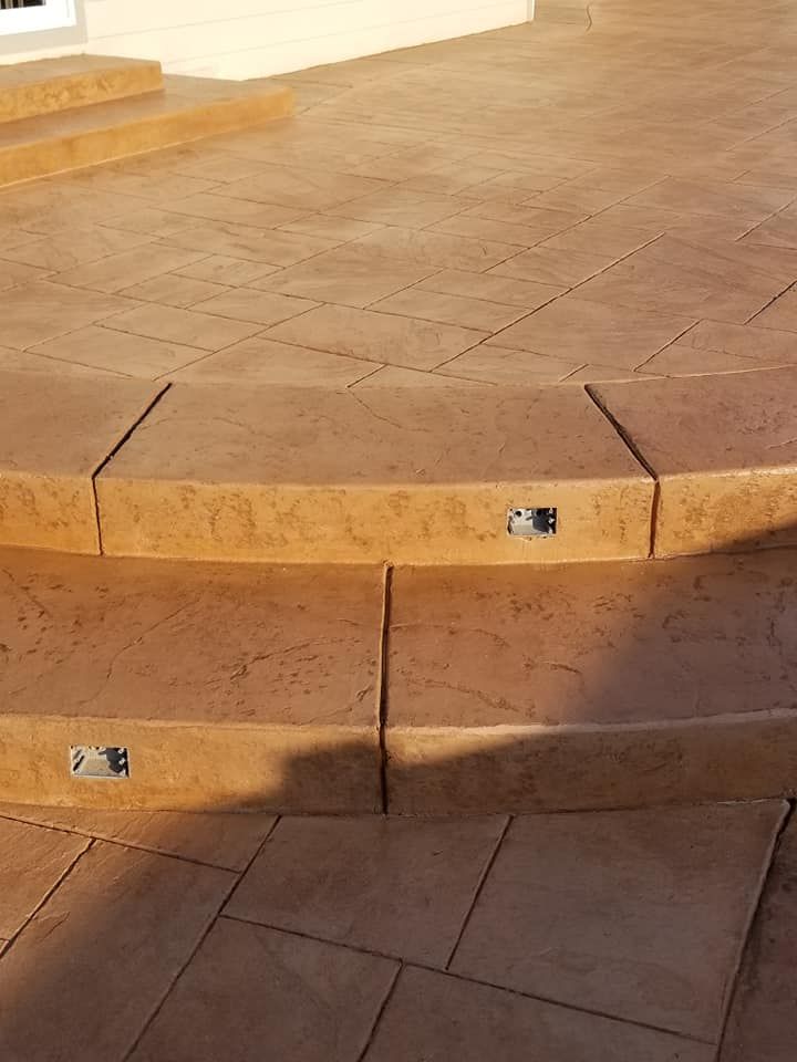Tan concrete steps and patio with embedded lighting.