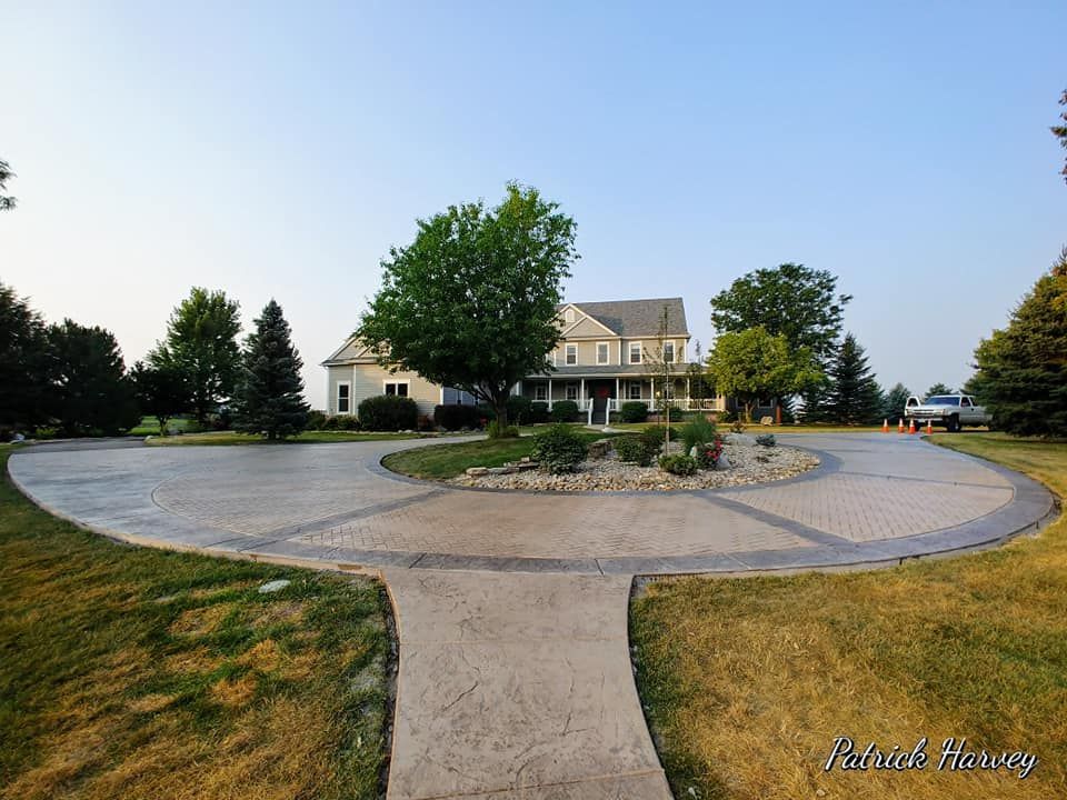 A large house with a circular driveway, landscaping and green grass.