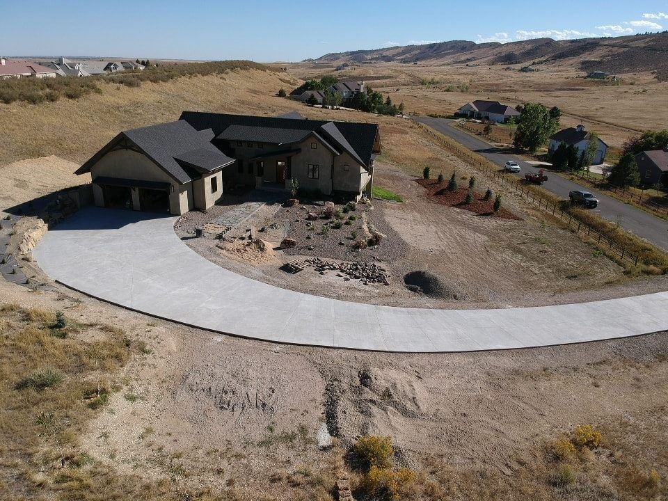 Modern home with curving driveway on a dry, hilly landscape.