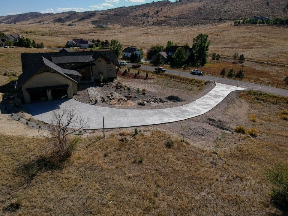 House with concrete driveway in a dry, rural setting.