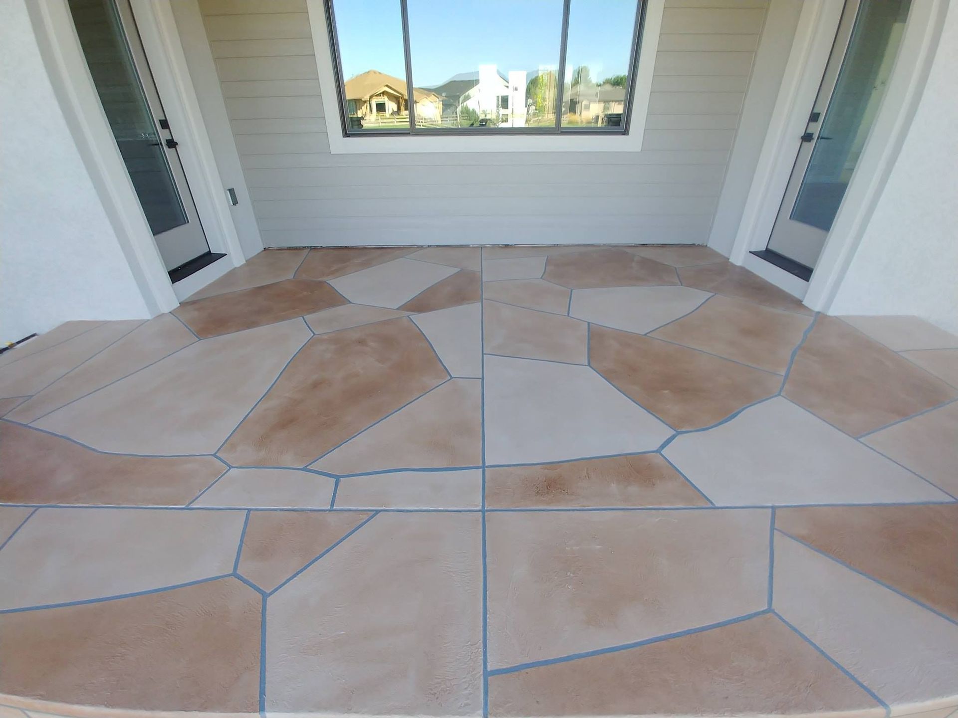 Patio with flagstone-patterned concrete floor, flanked by white walls and doors, with a window above.