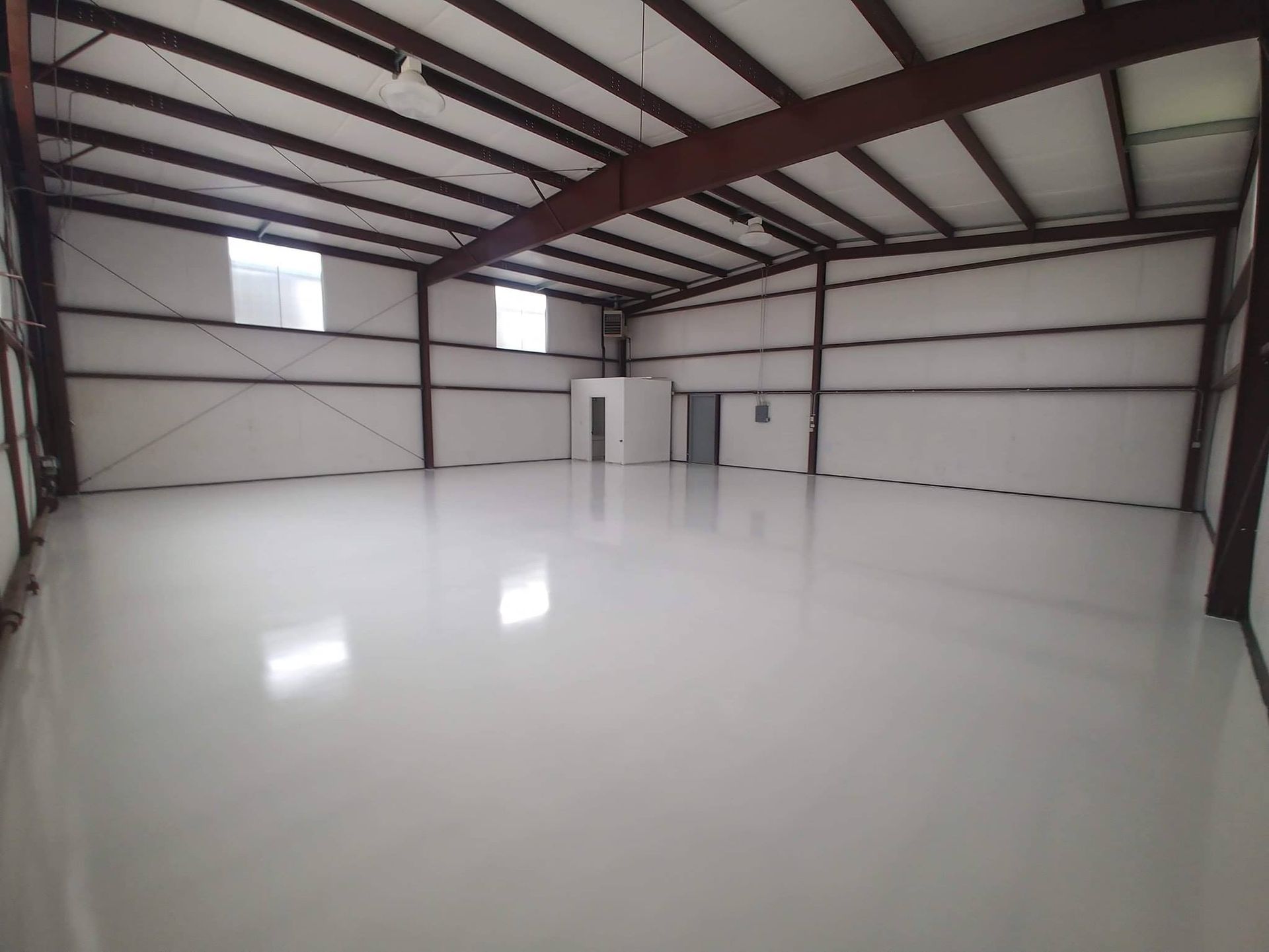 Empty warehouse interior with white walls and floor, metal beams.