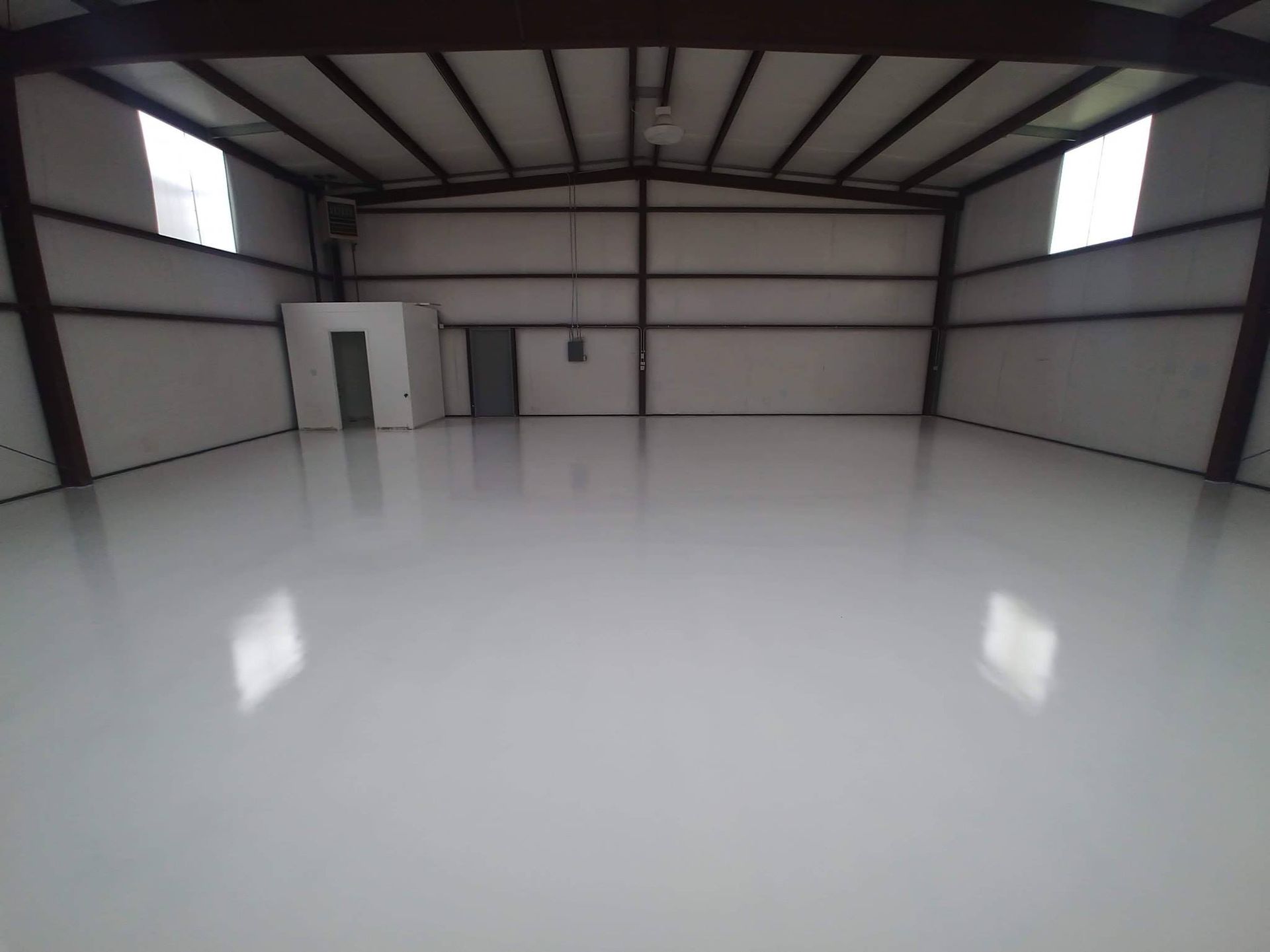 Interior of a large, empty warehouse with a bright white, reflective floor.